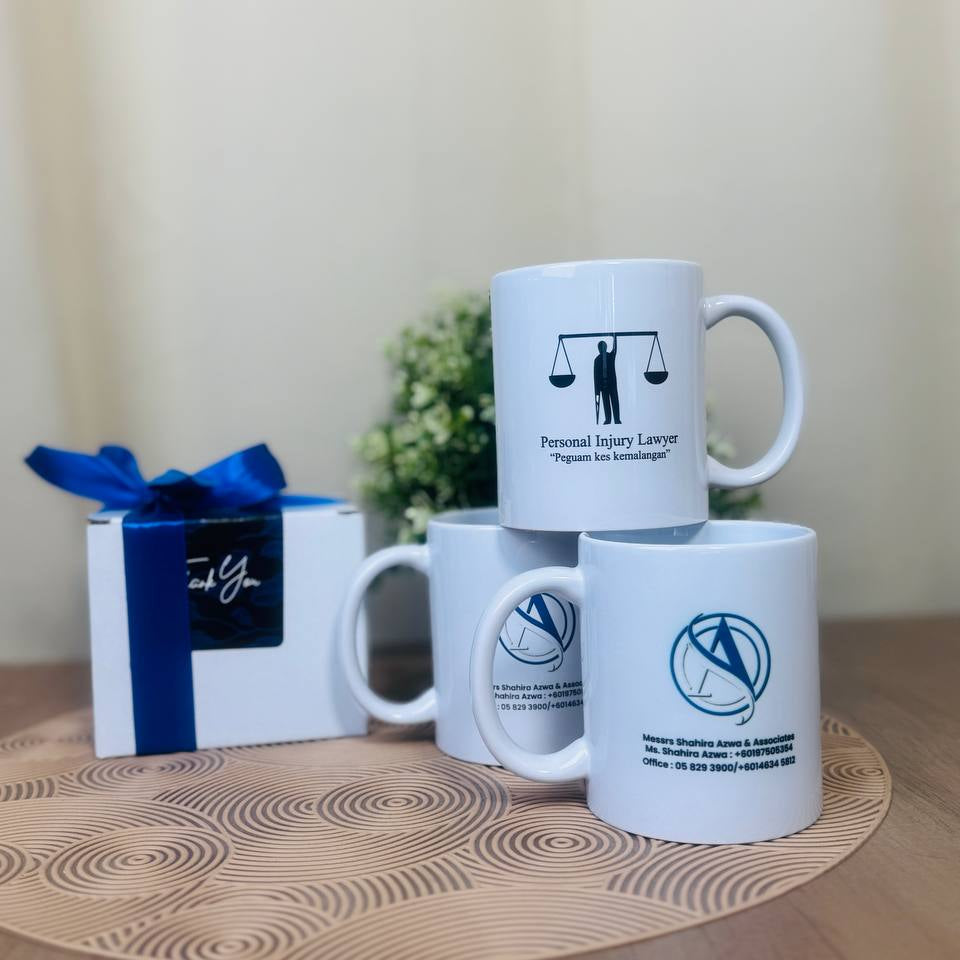 Corporate Gifts White mugs with legal-themed designs on a wooden surface with a gift box.