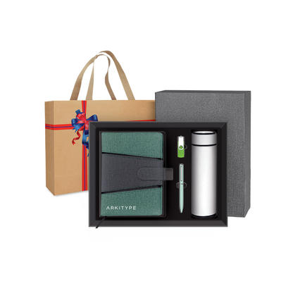 Gift set with a notebook, pen, and tumbler in a box, with a branded bag in the background.