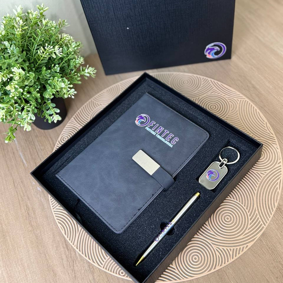 Corporate Gifts for Employees Set of stationery items including a pen, keychain, and card in a black box on a wooden surface with a plant in the background.